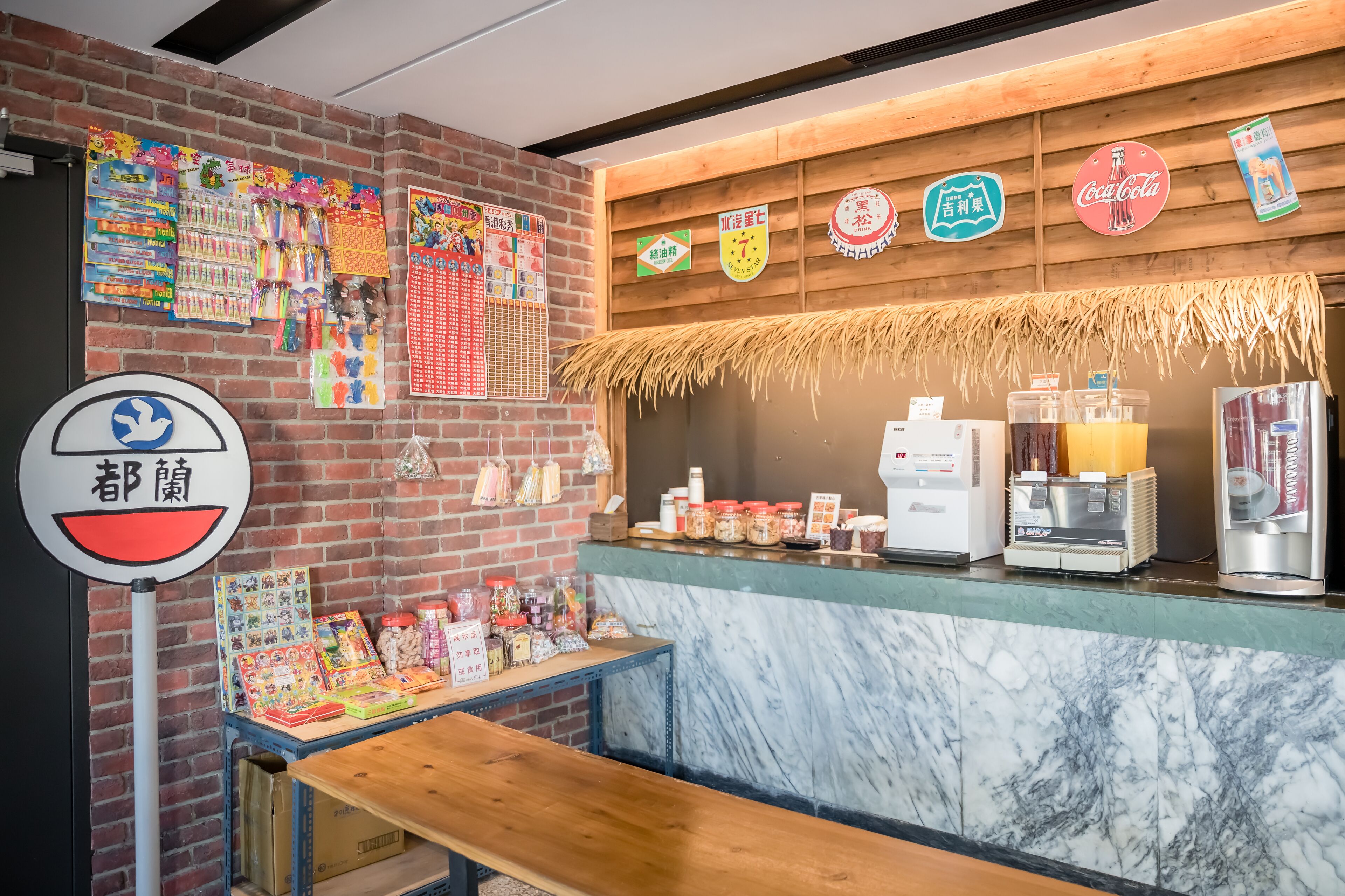 A cafe with a brick wall, wooden counter, and various food items displayed.