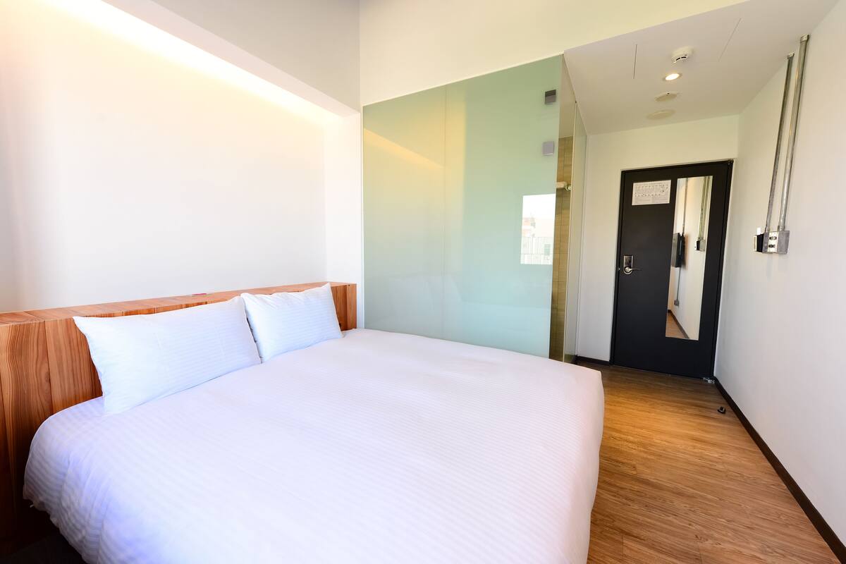 Une chambre d’hôtel avec un grand lit, une tête de lit en bois et un miroir au mur.