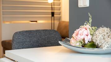 A modern room with a grey sofa, a white table, and a decorative plant arrangement.