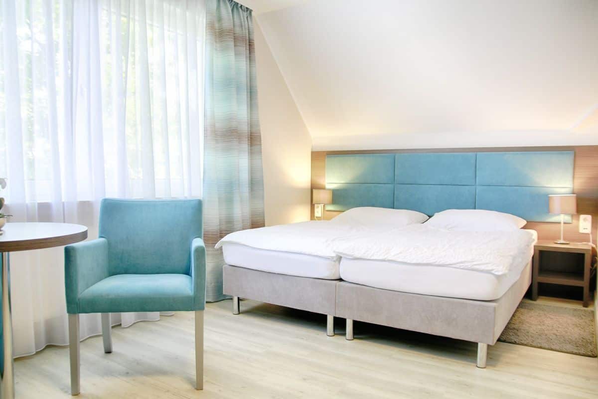 Een moderne hotelkamer met een bed, een stoel, een nachtkastje en een lamp.
