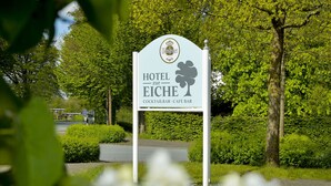 Un cartel de hotel con el nombre 'Hotel Eiche' que anuncia un bar de cócteles y un café.