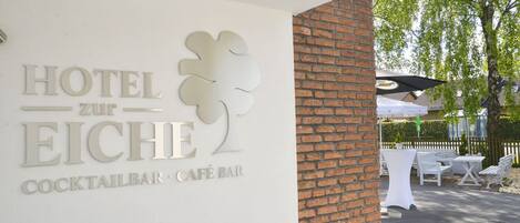 Placa de hotel com o logotipo de uma árvore e indica um bar de cocktails e um café-bar.