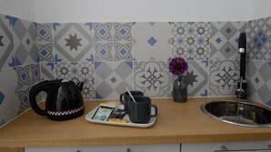 A kitchen counter with a kettle, a tray with a mug and a book, and a vase with a flower. - Hotel Terre Neuve (Paris)