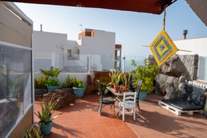 Un patio con una mesa y sillas, plantas en macetas y un adorno colgante.