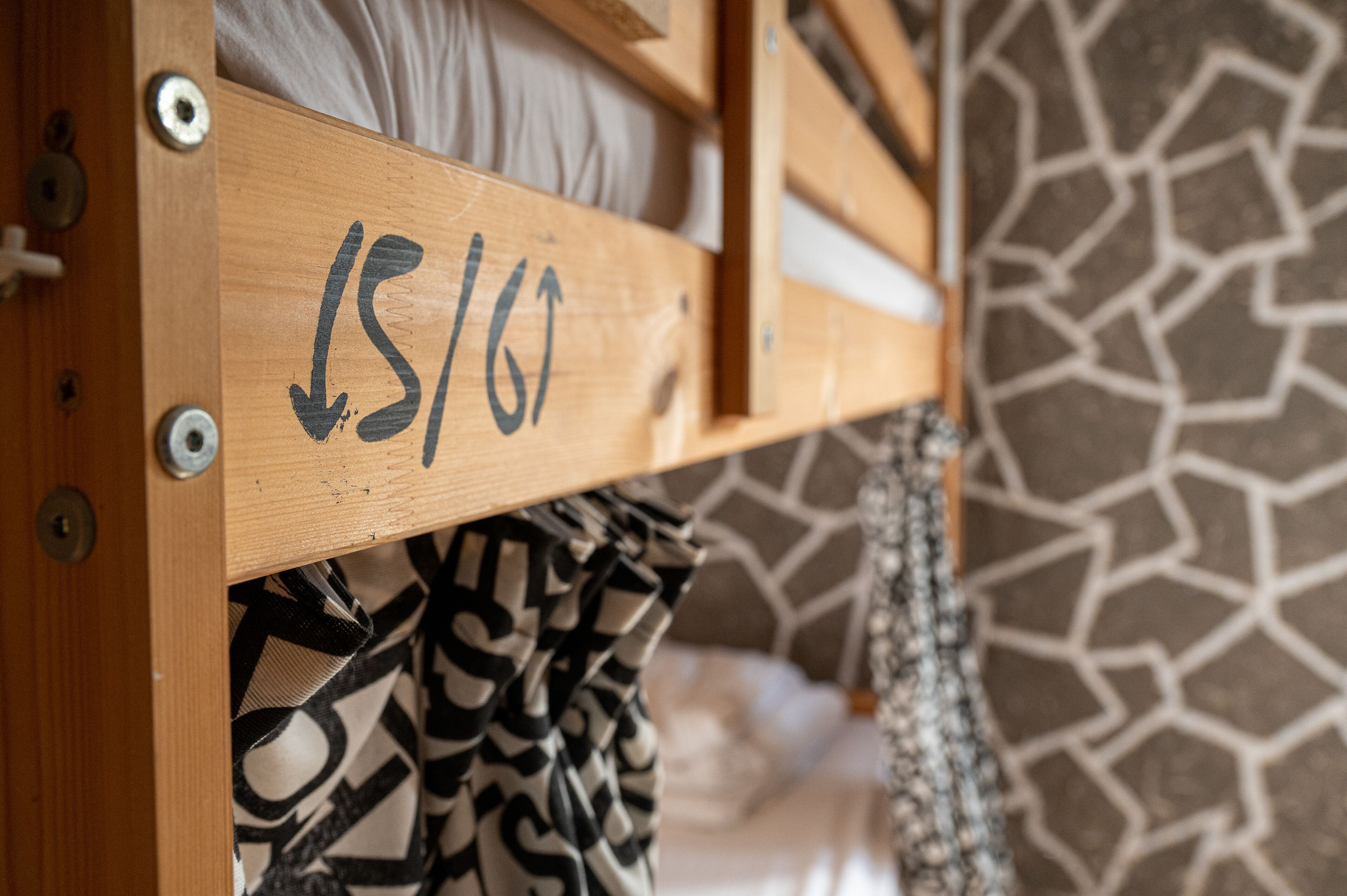 A wooden bunk bed with a number '151/6' and arrows indicating the direction to the bed.