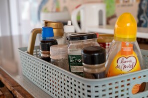 Ein Korb mit verschiedenen Küchenartikeln, darunter ein Glas 'Luna de Miel'-Honig, eine Kaffeeglas und weitere Gewürze.