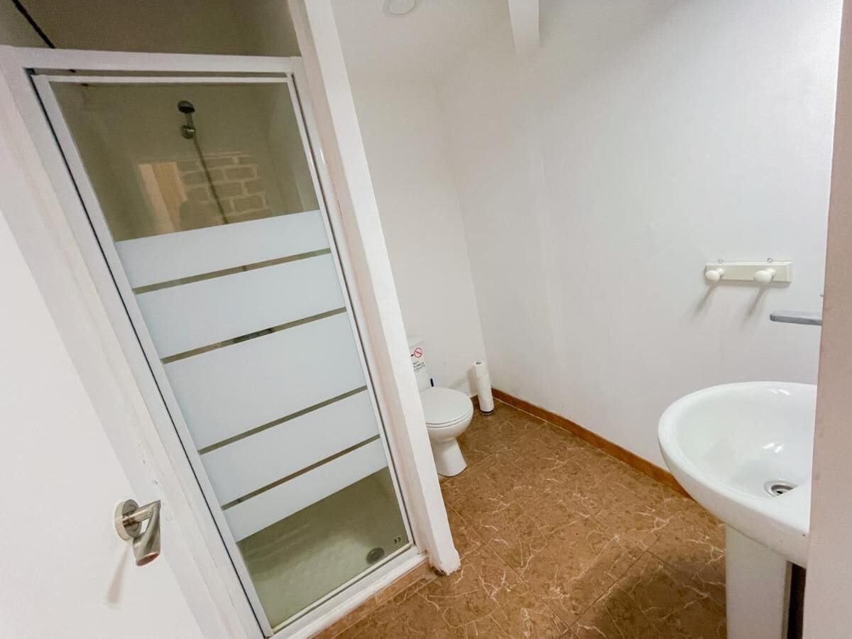 A bathroom with a glass door, a toilet, and a sink.