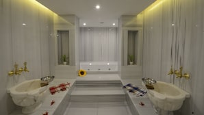Un baño moderno con dos lavamanos, una bañera y un espejo.