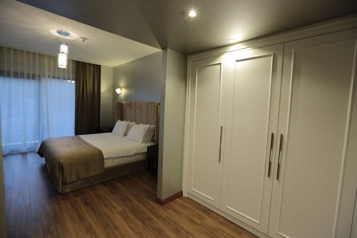 A hotel room with a bed, wardrobe, and a chandelier.