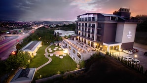 Un hotel de diseño moderno, con terraza en la azotea, mobiliario exterior y un jardín bien cuidado.
