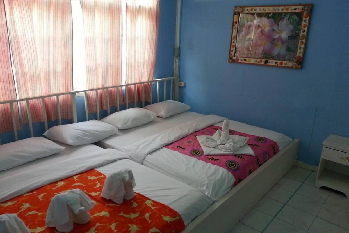 A hotel room with a bed, pillows, a bedside table, and a painting on the wall.