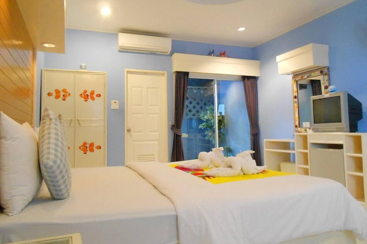 A bedroom with two beds, a TV, and a wardrobe.