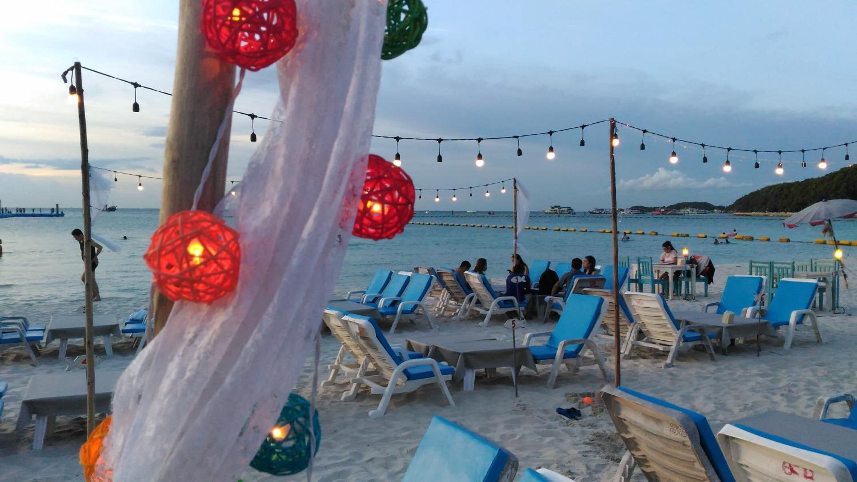 A beachside setting with lounge chairs and string lights.