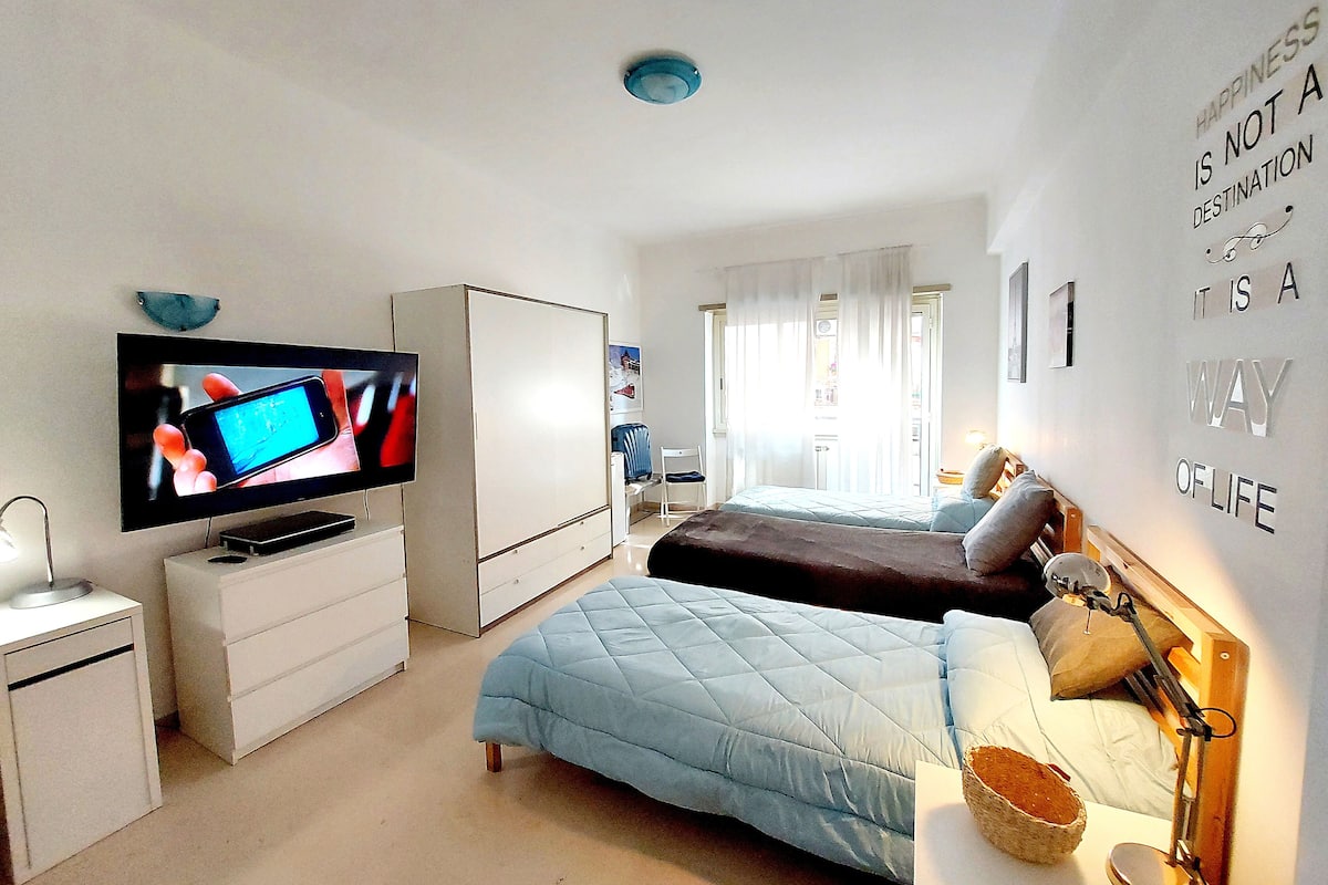 A bedroom with a TV, two beds, a wardrobe, and a wall with motivational text.
