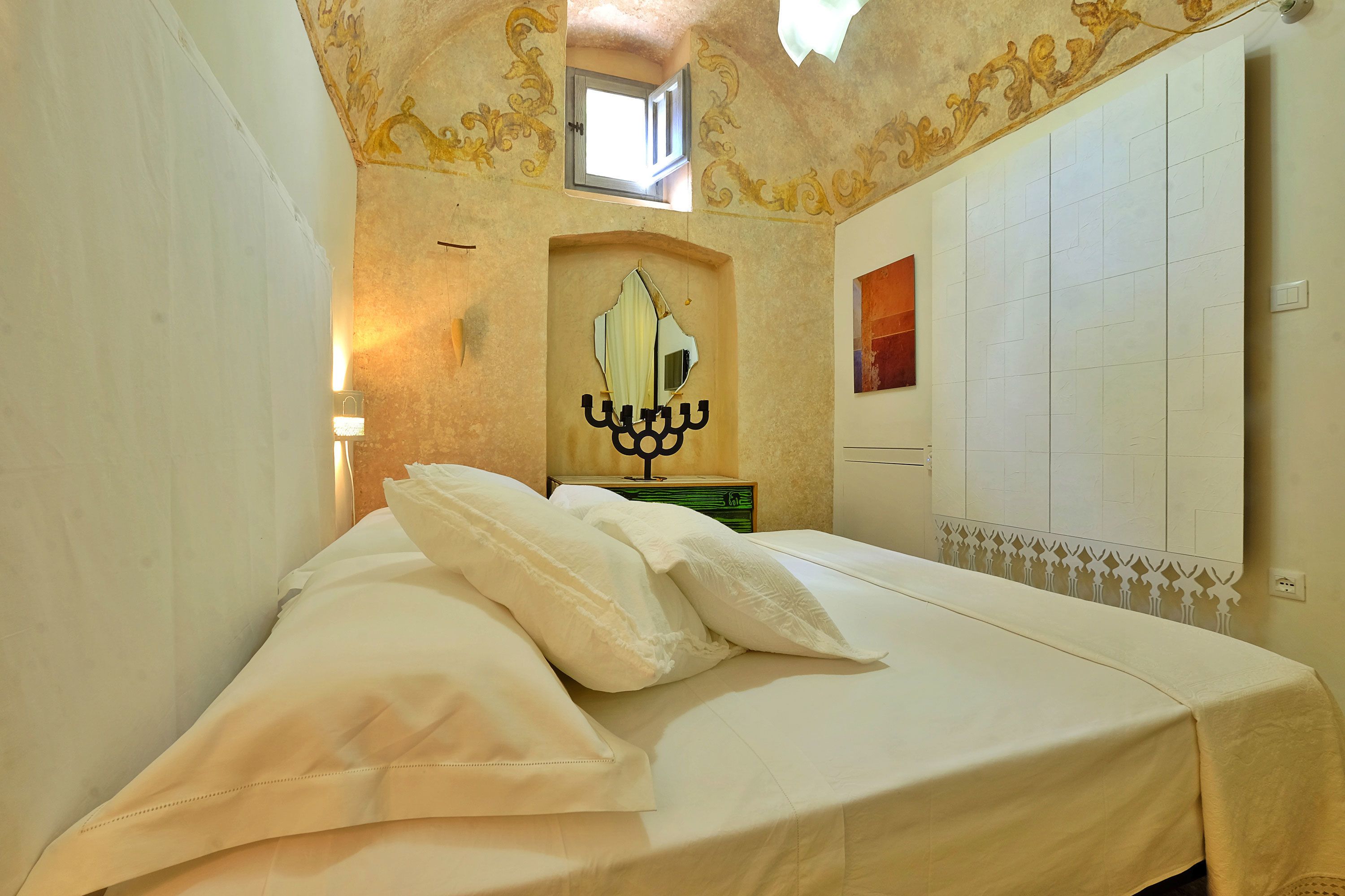 Ein Hotelzimmer mit Bett, Wandleuchte, dekorativem Spiegel und Heizkörper.