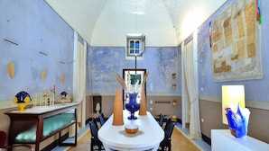 A dining area with a round table, chairs, a decorative vase, and a small window. - Biomasseria Muto (Ruffano)