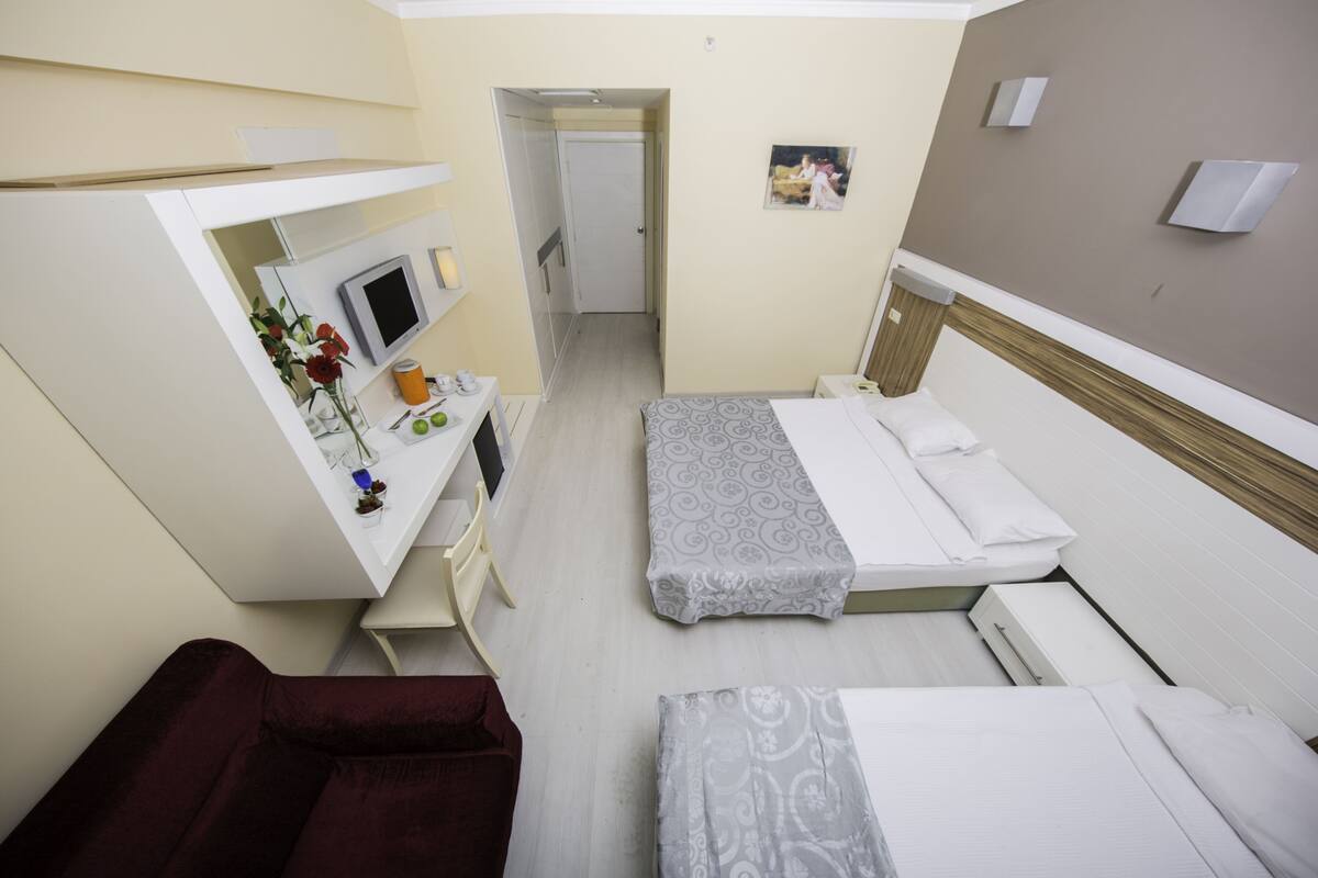 A compact hotel room with a bed, a desk with a computer, and a small seating area.