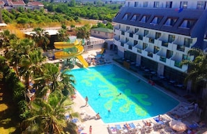 A hotel with a large swimming pool, a water slide, and a poolside area with lounge chairs. - Armir Resort - All inclusive (Kemer)