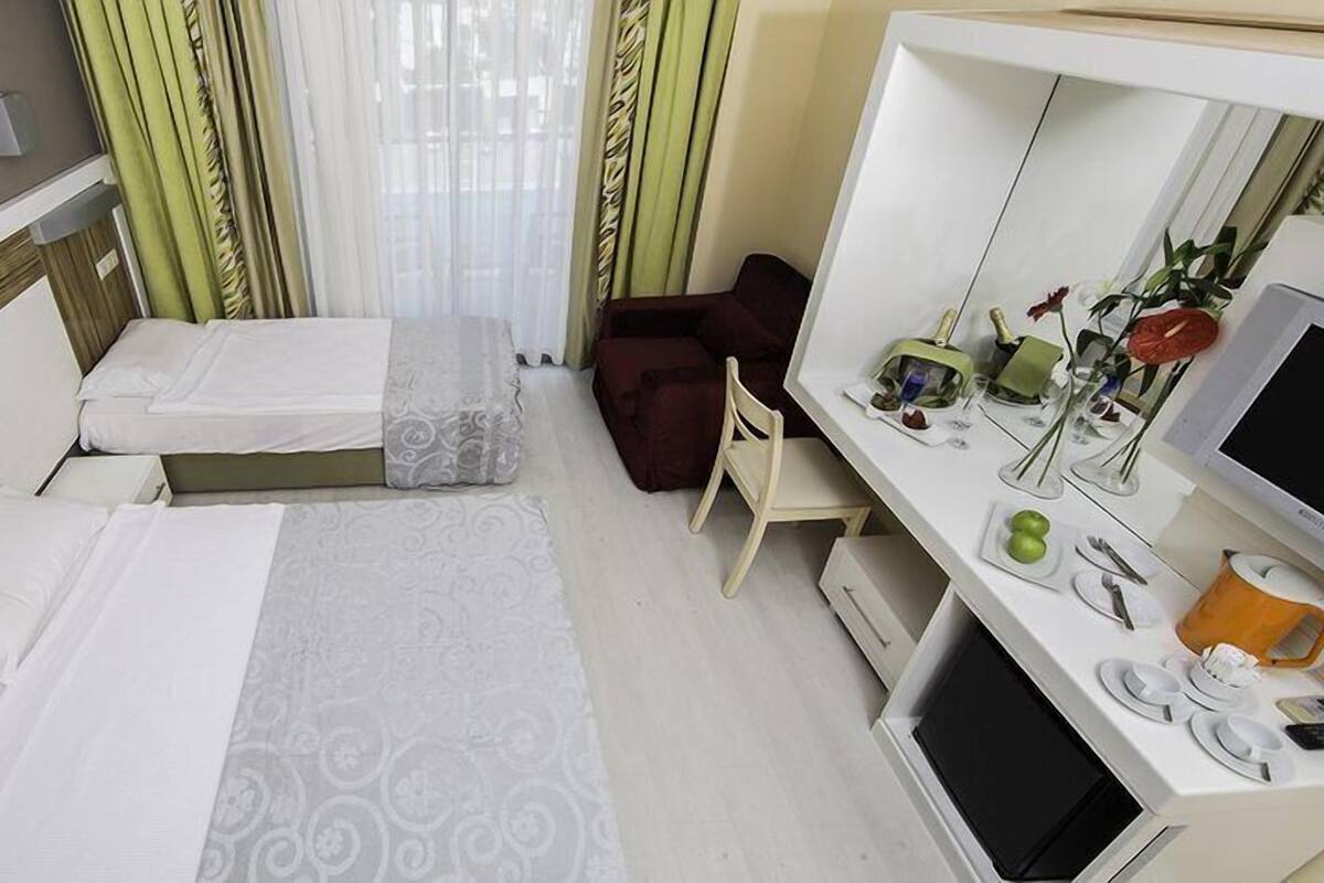 A hotel room with two beds, a desk with a computer, and a TV.