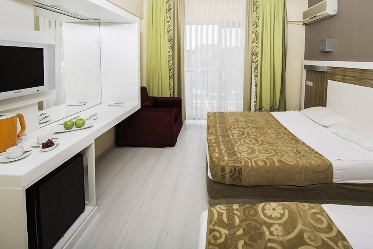 A hotel room with a bed, a desk with a TV, a microwave, and a small seating area.