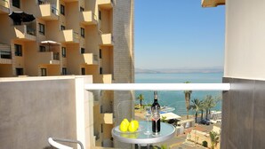 A balcony with a table and chairs, overlooking a coastal view with buildings and a clear sky. - Kings Towers Suite Apartments (Tiberias)