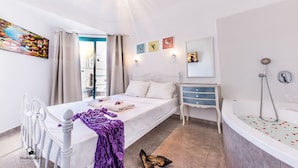 A bedroom with a bed, a vanity, a bathtub, and a window with curtains. - Kings Towers Suite Apartments (Tiberias)