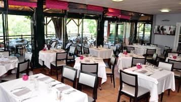 A restaurant with multiple tables set for dining, large windows, and a view of the outdoors.