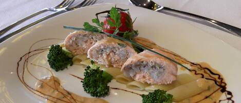 A white plate with a rolled meat dish, broccoli, and sauce.