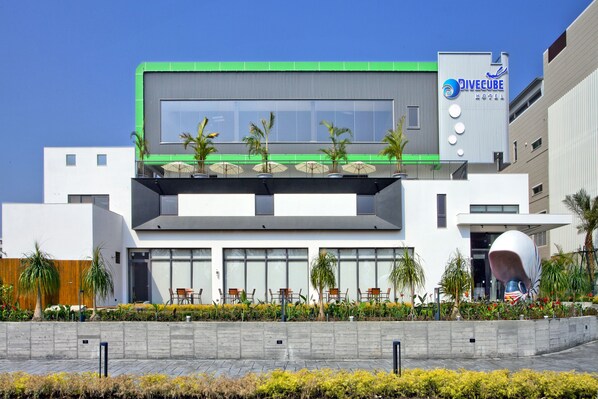 A modern hotel with a green accent, outdoor seating, and a distinctive sculpture. - DiveCube Hotel (Taichung)