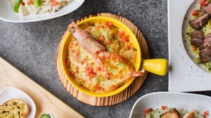 A yellow dish with a seafood item, possibly a lobster, on a wooden board. - DiveCube Hotel (Taichung)
