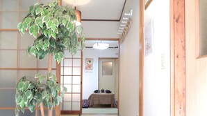 Un interior japonés tradicional con suelo de tatami, puertas correderas y una planta colgante.