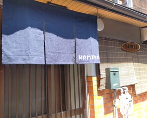 Une devanture de magasin avec un auvent bleu sur lequel est inscrit le nom « NAMIYA ».