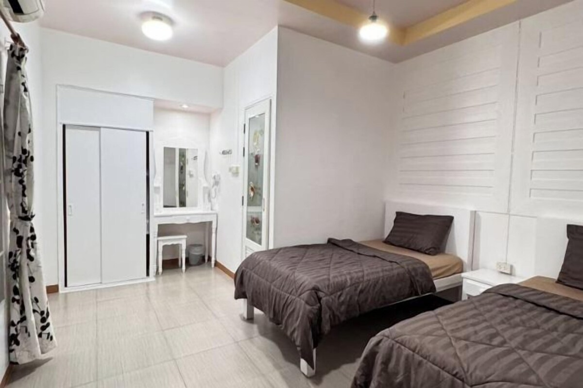 A bedroom with two beds, a desk, and a wardrobe.