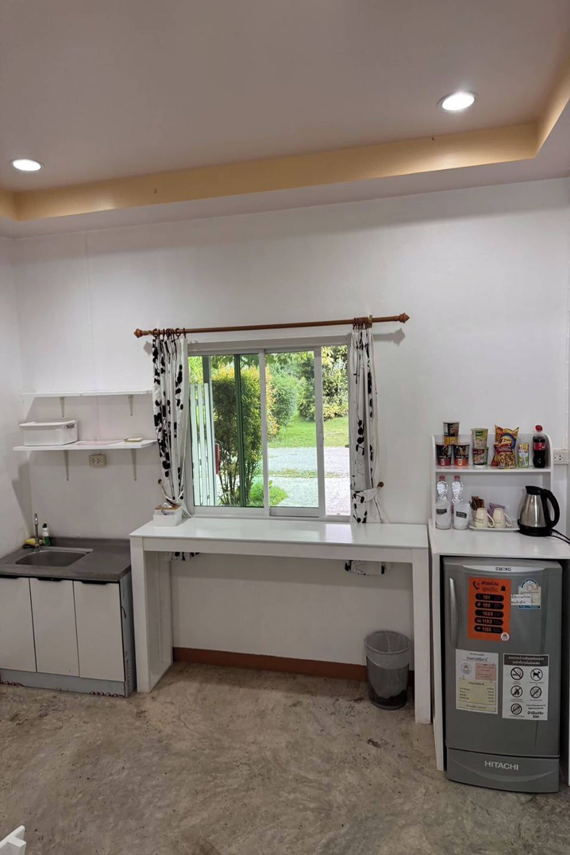 Una cocina funcional con ventana, un lavamanos, un microondas y un refrigerador.