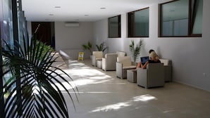 Un lobby amplio con mobiliario moderno, ventanas grandes y plantas de interior.