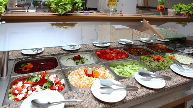 A buffet with various food options and utensils.