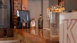 A bar area with a coffee machine, bottles of liquor, and a large glass container. - Powder Temple (Hakuba)