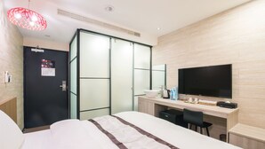 A hotel room with a bed, a desk with a flat-screen TV, a wardrobe, and a modern light fixture. - Sunrise Business Hotel Ximen (Taipei)