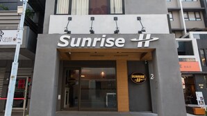 A modern hotel with a sign reading "Sunrise Hotel." It features a prominent entrance with a glass facade and a wooden accent. - Sunrise Business Hotel Ximen (Taipei)