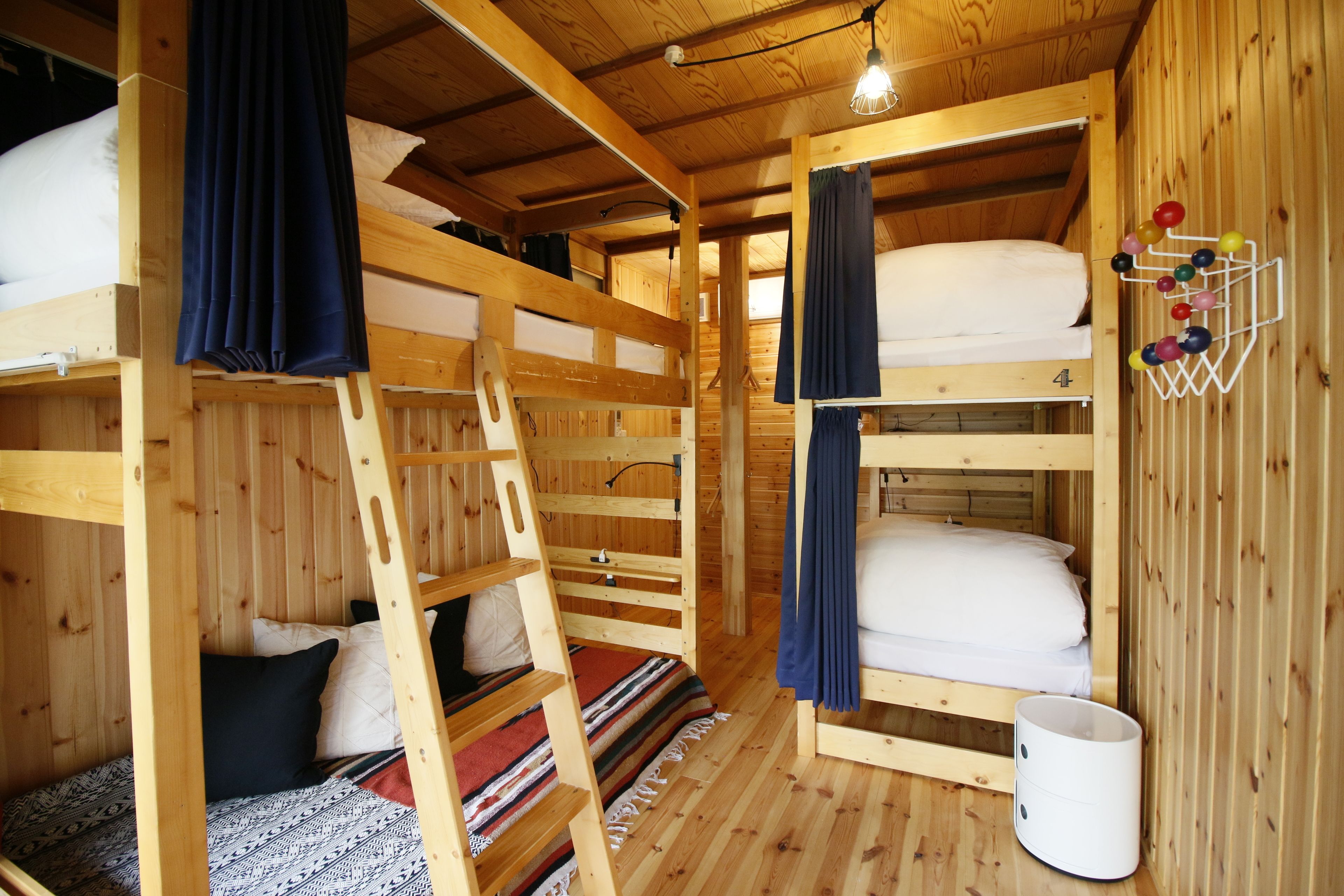 A wooden cabin with bunk beds, a ladder, and a hanging ball rack.