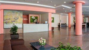 A reception area with a receptionist, a reception desk, and a large floral painting on the wall. - Aronia Beach - All Incusive - All inclusive (Sunny Beach)