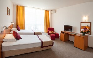 A hotel room with two beds, a desk, a TV, and a mirror.