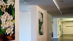 A hallway with framed floral artwork on the walls, a restaurant sign, and a clean, modern interior design. - Aronia Beach - All Incusive - All inclusive (Sunny Beach)