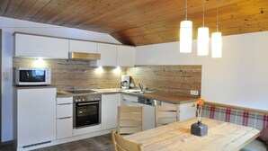 Een moderne keuken met witte kastjes, een houten plafond en hangende lampen.