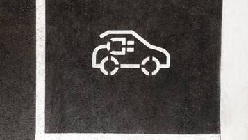 A parking sign with a car and a plug symbol, indicating electric vehicle charging.