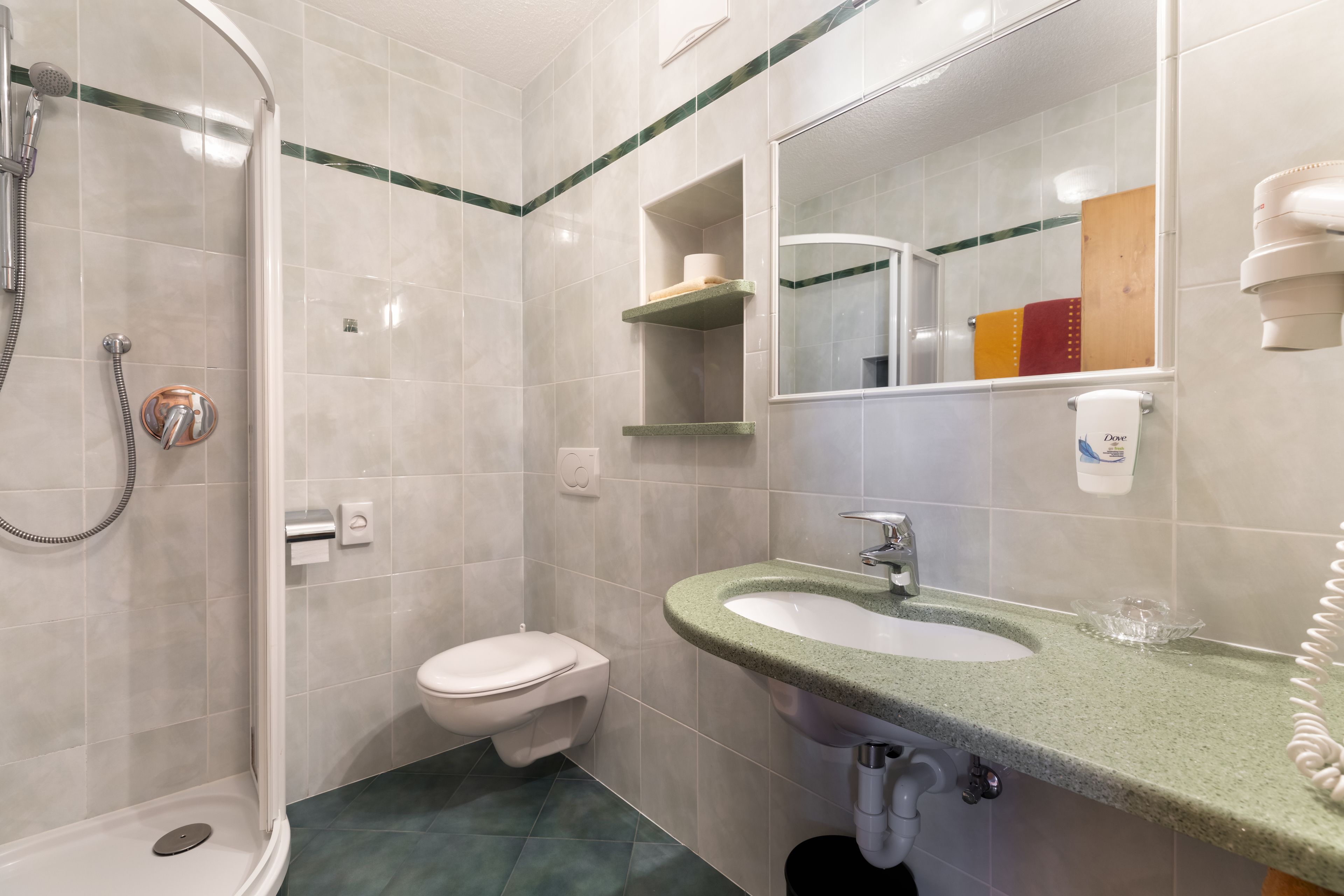 Un bagno con doccia, WC, lavandino e specchio.