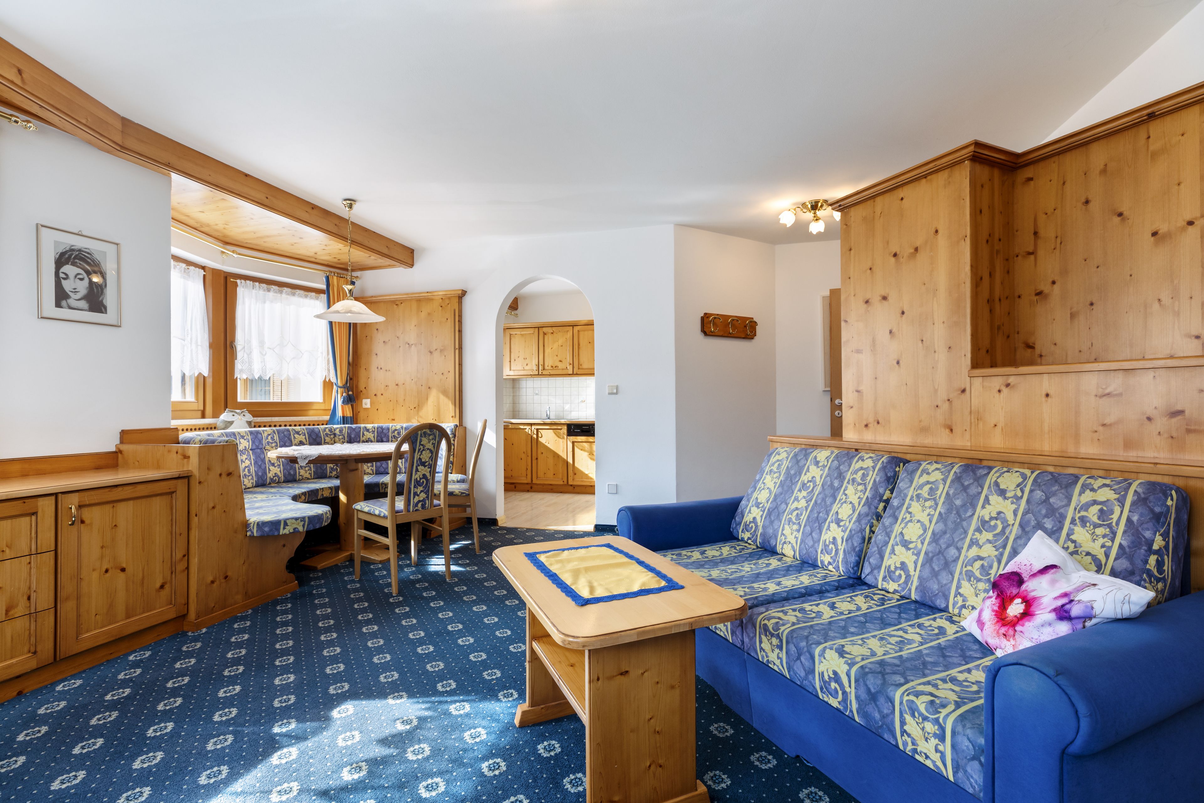 A compact living space with a sofa, a small table, a dining area, and wooden cabinetry.