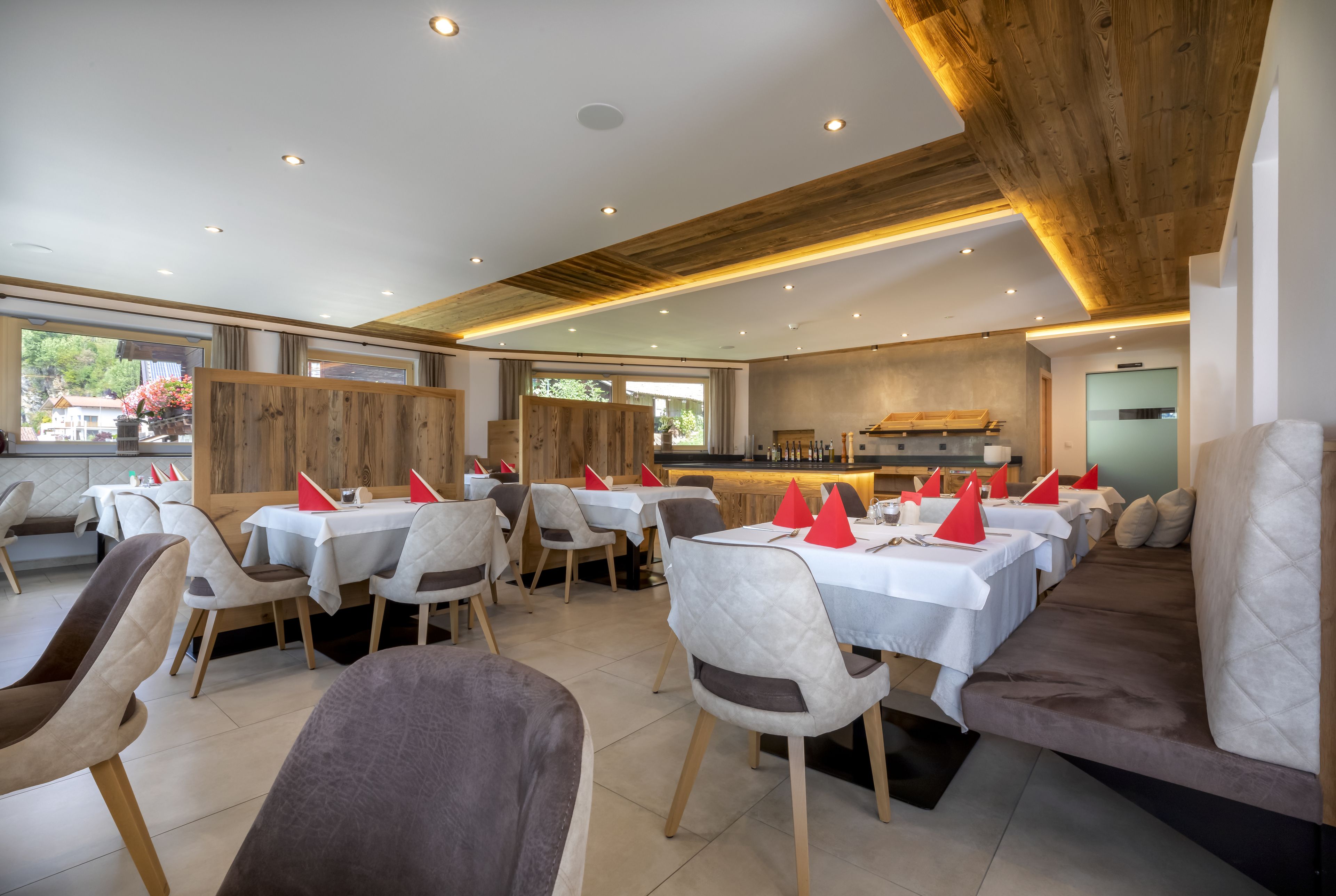 A restaurant with multiple dining tables and chairs, a wooden ceiling, and a view of the outdoors.