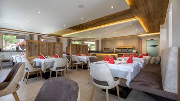 A restaurant with multiple dining tables and chairs, a wooden ceiling, and a view of the outdoors.