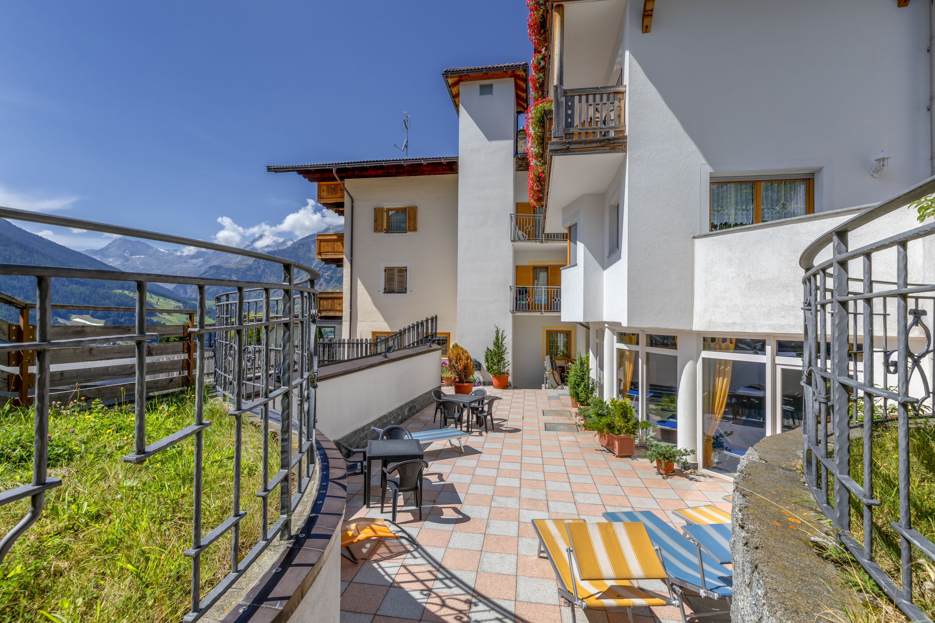 A hotel courtyard with outdoor seating, potted plants, and mountain views.